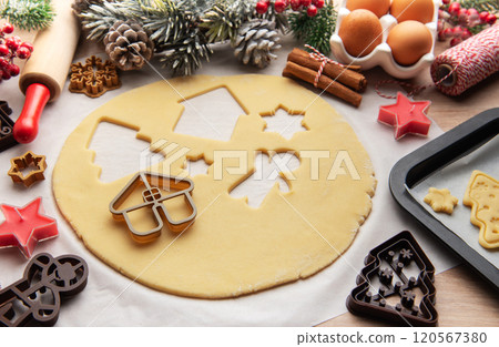 Baker is preparing christmas cookies using dough cutters and baking tray 120567380