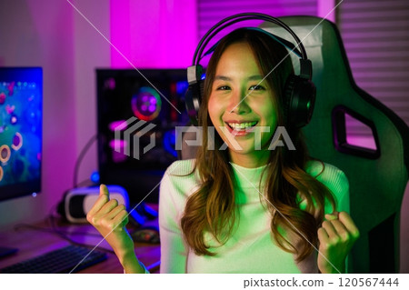 Winning Victory. Asian gamer playing online video game excited on desktop computer PC colorful neon LED lights, young woman in gaming raise hand to enjoying happy successful, E-Sport, front view 120567444