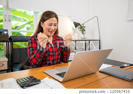 Asian Adult business woman indoors in home office working on laptop computer, happy female freelancer sitting at the home work on new project, businesswoman shopping online with computer 120567458
