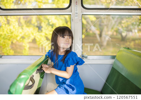 A girl in blue clothes sits on a retro city bus in autumn A girl in blue clothes sits on a retro city bus in autumn 120567551