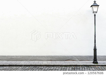 Vintage street lamp next to a blank white wall in a quiet alley 120567686