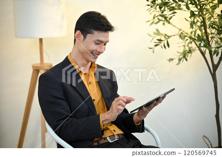 Smiling asian executive reviewing information on digital tablet in a bright office space Smiling asian executive reviewing information on digital tablet in a bright office space 120569745