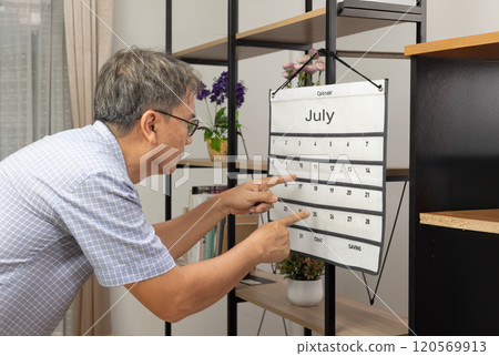 Confused Asian Senior Man With Dementia Looking At Wall Calendar. Confused Asian Senior Man With Dementia Looking At Wall Calendar. 120569913
