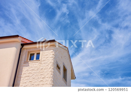 Modern Mediterranean house with red tile roof and white stone facade under bright blue sky. Typical architecture of residential building in coastal town 120569951