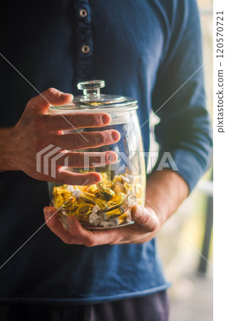 man in blue shirt holding the glass jar with candy . High quality photo 120570721