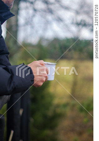 male in black jacket holding the metal cup in forest . High quality photo male in black jacket holding the metal cup in forest . High quality photo 120570728