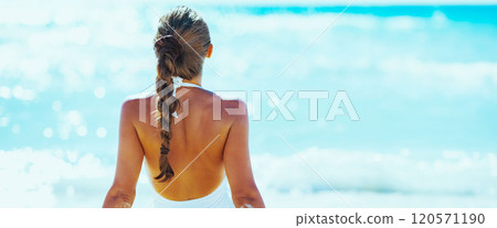 Young woman sitting at seaside. rear view 120571190