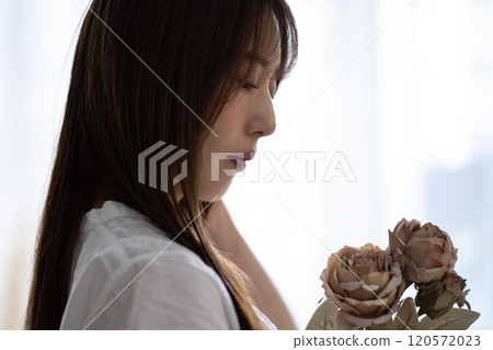 長黑髮的年輕女子，手持白花 120572023