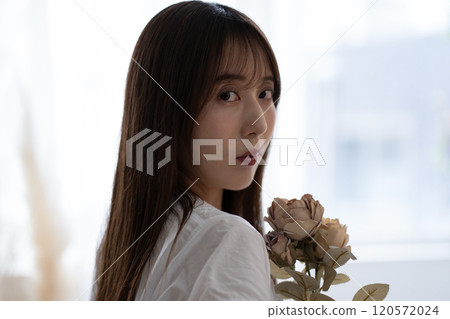 長黑髮的年輕女子,手持白花 長黑髮的年輕女子,手持白花 120572024