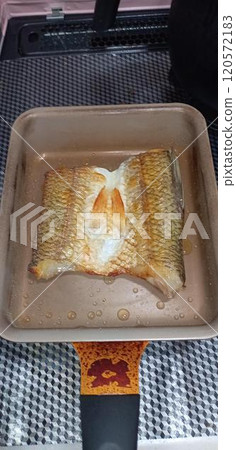 Dried fish is being fried in a frying pan 120572183