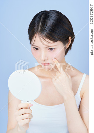 一名年輕女子檢查她的皮膚 一名年輕女子檢查她的皮膚 120572967