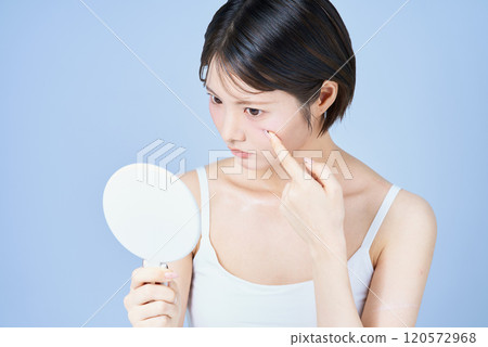 一名年輕女子檢查她的皮膚 一名年輕女子檢查她的皮膚 120572968