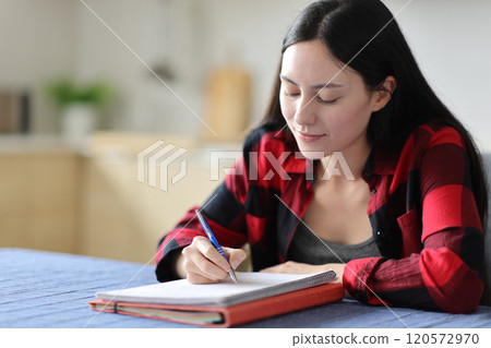 Asian student taking notes studying at home Asian student taking notes studying at home 120572970
