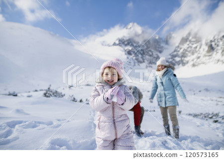 Portrait of small girl enjoying winter holiday in the mountains with family, playing in snow, having snowball fight. Portrait of small girl enjoying winter holiday in the mountains with family, playing in snow, having snowball fight. 120573165