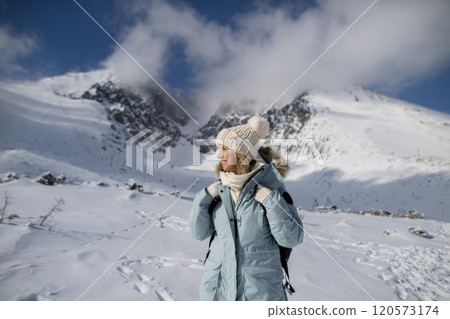Woman standing in the middle of the snowy nature looking at the winter landscape around her, smiling. Woman standing in the middle of the snowy nature looking at the winter landscape around her, smiling. 120573174
