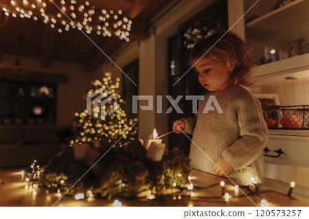 Little girl lighting candles on advent wreath. Little girl lighting candles on advent wreath. 120573257