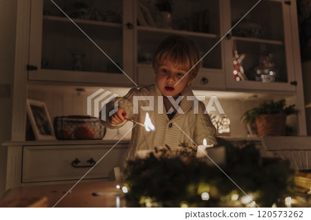 Little boy lighting candles on advent wreath. 120573262