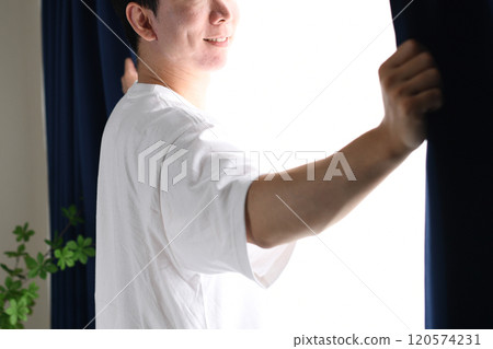 Asian man opening the curtains and basking in the sunlight 120574231