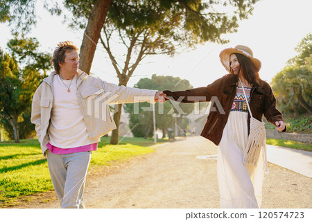 A Couple Walking Hand in Hand in a Beautiful, Scenic Park Filled with Lush Greenery and Sunshine 120574723