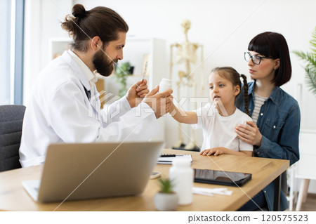 Doctor providing medication to child with mother in modern clinic Doctor providing medication to child with mother in modern clinic 120575523