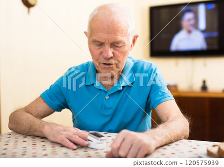Worried elderly man measuring himself oxygen saturation at home Worried elderly man measuring himself oxygen saturation at home 120575939