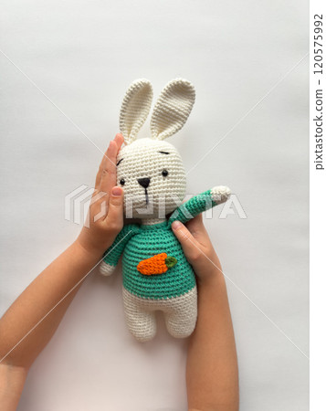 Child embracing crochet bunny with carrot sweater. Cozy playtime theme Child embracing crochet bunny with carrot sweater. Cozy playtime theme 120575992