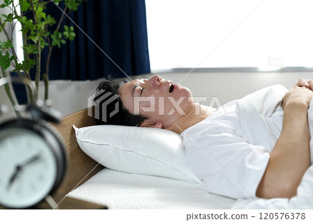 Asian man sleeping on bed with his mouth open Asian man sleeping on bed with his mouth open 120576378