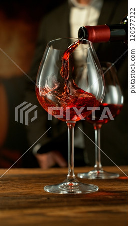 Close-up of red wine pouring into glass in wine cellar , freeze motion. 120577322