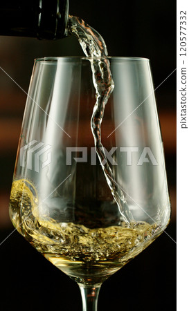 Close-up of white wine pouring into glass , freeze motion. 120577332