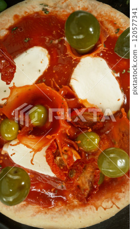 Super slow motion of falling various ingredients on pizza dough with sugo, top down view Super slow motion of falling various ingredients on pizza dough with sugo, top down view 120577341