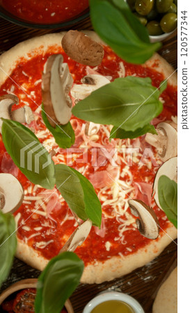 Super slow motion of falling various ingredients on pizza dough with sugo, top down view Super slow motion of falling various ingredients on pizza dough with sugo, top down view 120577344