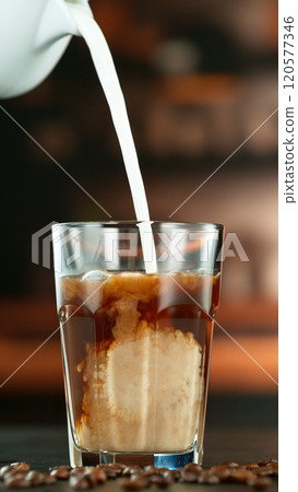 Freeze Motion Shot of Pouring Milk into Coffee in a Cafe 120577346