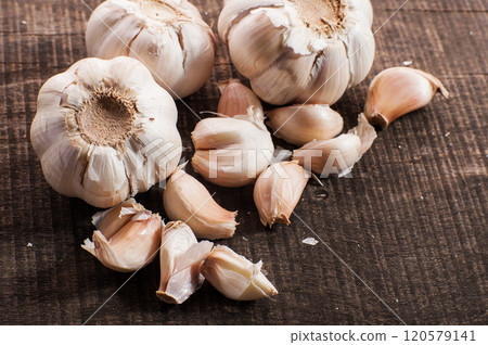 Two pieces of fresh garlic useful trace elements.White garlic bulbs and peeled garlic in ceramic bowl on rough green old wooden background. 120579141