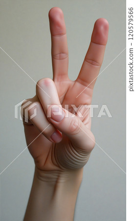 Hand gesturing peace sign on neutral background 120579566