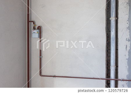 Gas counter with gas pipes in a corner of new unfinished apartment or house. 120579726