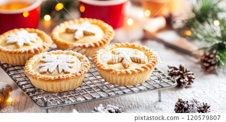 Warm mince pies, adorned with festive patterns, cool on a rack surrounded by seasonal decorations and baking tools 120579807