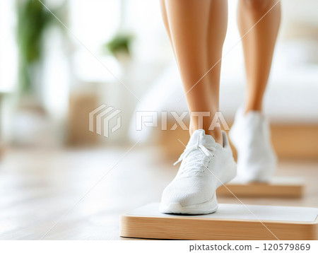 A person wearing white sports shoes stepping on a fitness platform 120579869