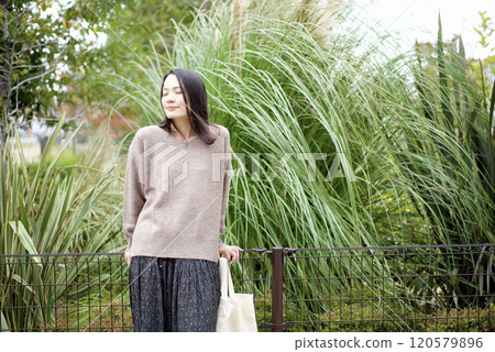 A woman standing with plants in the background 120579896