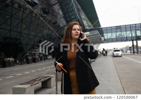 Traveler business 30s woman with suitcase calling mobile phone waiting yellow taxi on road in city street. Beautiful female smiling using smartphone application hailing with hand up calling cab 120580067