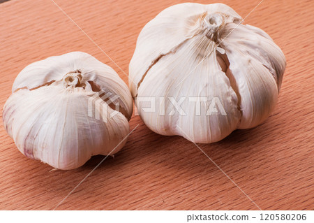 garlic on wooden surface.White garlic bulbs and peeled garlic in ceramic bowl on rough green old wooden background. 120580206