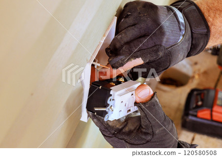 Installs electrical outlets sockets on exterior facade of house by an electrician Installs electrical outlets sockets on exterior facade of house by an electrician 120580508