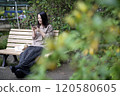 A woman looking at a smartphone on a park bench 120580605