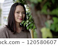Woman standing next to a tree 120580607