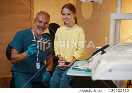 Portrait Of Dentist And Young Patient Smiling In Clinic 120582410
