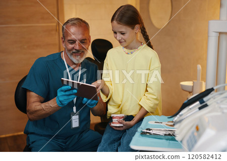 Smiling Dentist Showing Procedure On Tablet Screen 120582412