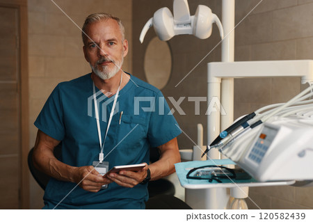 Portrait of Mature Dentist Wearing Whistle While Holding Phone Portrait of Mature Dentist Wearing Whistle While Holding Phone 120582439