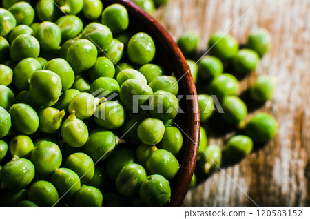 Beans and pods of green peas are in a bowl on a wooden surface.green sweet peas on a dark wooden background, still life, concept of fresh and healthy food Beans and pods of green peas are in a bowl on a wooden surface.green sweet peas on a dark wooden background, still life, concept of fresh and healthy food 120583152