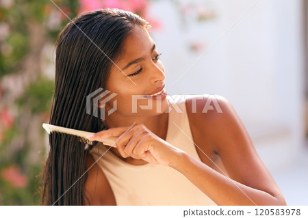Healthy Hair Care Routine: Woman Relaxing While Gently Combing Hair 120583978
