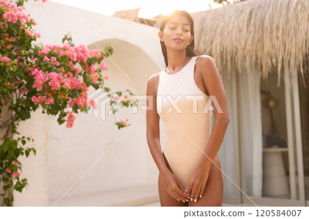 Elegant Woman Embracing Sunlight in Resort Garden Setting Elegant Woman Embracing Sunlight in Resort Garden Setting 120584007