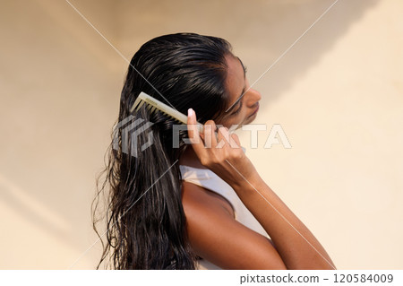 Woman Combing Long Wet Hair in Natural Sunlight Setting Woman Combing Long Wet Hair in Natural Sunlight Setting 120584009